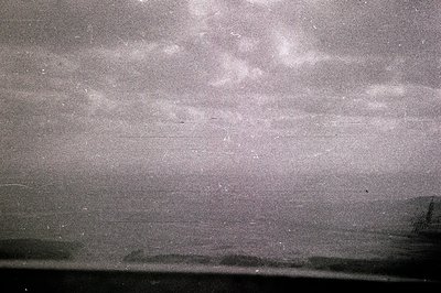 Ethereal seascape with dark foreground & turbulent sky. Heavily scratched & aged monochrome print, evoking a sense of nostalg...