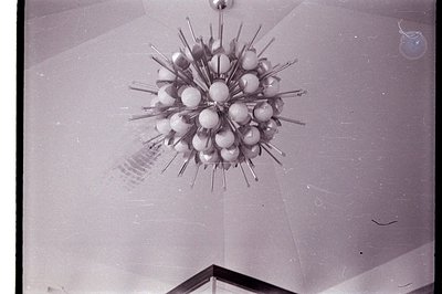 Striking Sputnik-style chandelier dominates this view, featuring radiating silver arms and frosted glass globes. The fixture'...