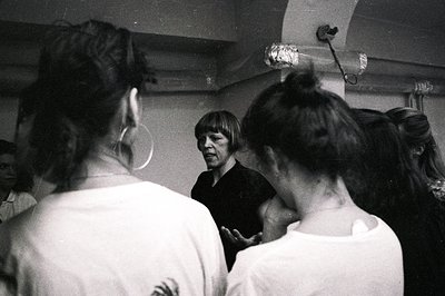 A candid moment captures a man seemingly addressing a group of young people, likely in a studio or rehearsal space. Visible d...