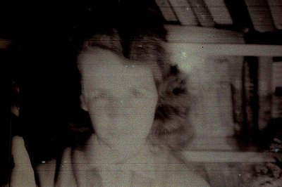 Close-up portrait, likely a candid snapshot, shows a smiling individual with short hair. Visible grain and vertical scratches...