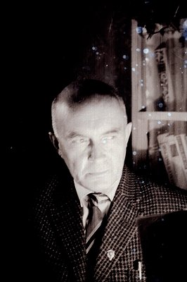 A portrait of a distinguished gentleman in a tweed suit and striped tie, posed formally near a large, ornate window. Likely 1...