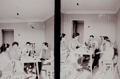 A group of young adults gathered around a table in a modestly furnished room. Appears to be a photo studio setup, judging by ...
