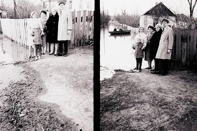 A family stands near a flooded area, likely their property. Three children and two adults pose near a weathered wooden fence....