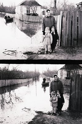 Flooded residential scene, likely Eastern Europe. A woman in a coat stands with two young children in a submerged courtyard. ...