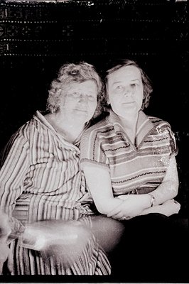 Two women in what appears to be a domestic setting. The subject on the left wears a striped, buttoned garment. The woman on t...