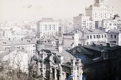 A high-angle, grayscale view of a European cityscape featuring ornate, multi-story buildings with detailed facades and tiled ...