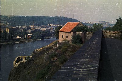 Overlooking a river valley, this image captures an industrial landscape with a small stone building topped with a red tile ro...