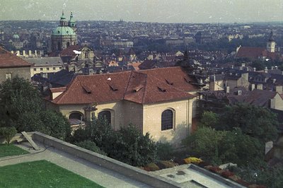 An elevated view of St. Vitus Cathedral and Prague Castle, Czech Republic. The foreground features a stone building with a ti...