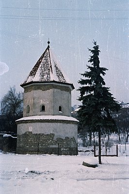 Charming, weathered stone rotunda with a tiled conical roof, likely a chapel or monument. Surrounded by a low stone wall and ...