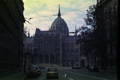Ornate Neo-Gothic architecture of the Hungarian Parliament Building dominates the view, framed by buildings and power lines. ...