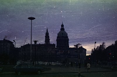 Nighttime cityscape captures a grand, ornate building—likely a cathedral or government structure—with twin towers and a promi...