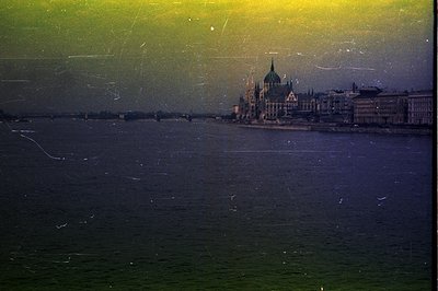 A wide view of the Danube River showcases the Hungarian Parliament Building, a Neo-Gothic landmark. A bridge extends into the...