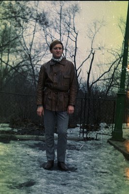 Man in a leather field jacket and corduroy shirt stands amidst light snow. Tapered trousers and boots complete the 1970s styl...