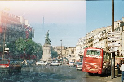 Parisian street scene. A red double-decker bus (likely a tourist route) dominates the right foreground, with a monumental equ...