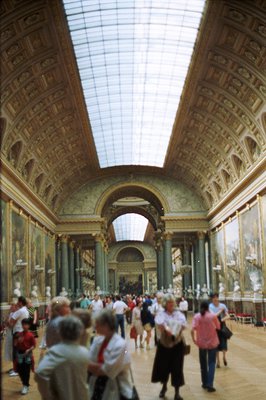 A wide-angle view captures the expansive Galerie des États at the Louvre Museum. Detailed, ornate ceiling moldings line the h...