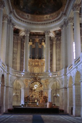 Stunning view of a Baroque-era church interior. Features colossal columns, an ornate gilded pipe organ, and intricately detai...
