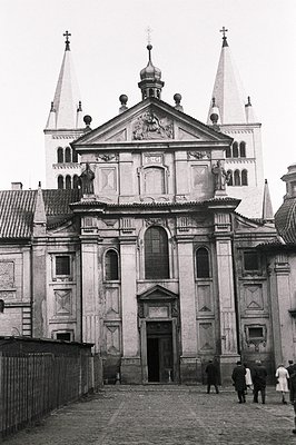 Ornate Baroque facade of a church with twin towers, detailed carvings, and a central dome. Cobblestone plaza in foreground wi...