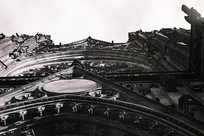 Intricate detail of a Gothic cathedral’s exterior ornamentation. Carved stone tracery features repeating circular motifs and ...