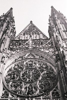 Striking upward view of a Gothic cathedral facade showcasing an intricate rose window and elaborate stone tracery. Steeply po...