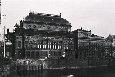 Opulent waterfront building, possibly a theater or grand hotel, features a prominent dome with statues. Architectural details...