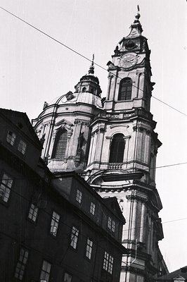 Ornate Baroque church tower rises above surrounding buildings. Facade features classical columns, pilasters, and a central cl...