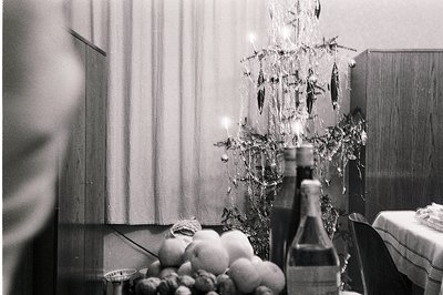 A decorated interior features a mirrored Christmas tree adorned with hanging ornaments, positioned in front of draped curtain...