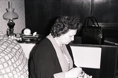 A woman, likely in a public space (waiting room?), is depicted smoking, deeply engrossed. She wears a dark jacket over a lacy...
