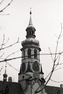 Ornate, Baroque-style church tower with clock face and tiered dome topped by a spire. Detailed stone carvings, arched windows...