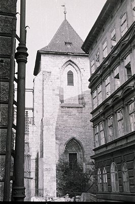 Black and white image showcases a medieval gate tower, likely part of a city wall. Constructed of light-colored stone, the to...