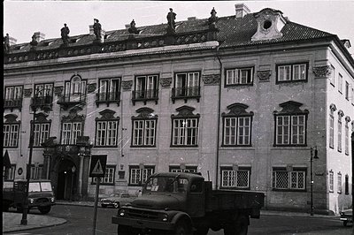 Grand, stucco-faced building featuring ornate balconies & decorative window frames. Visible street scene with a vintage truck...
