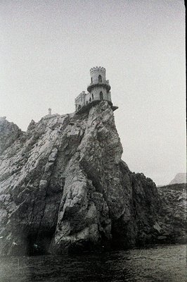 Dramatic black and white photograph of Kaliakria Cape, Bulgaria. A stone tower with crenellations sits atop a rugged, rocky h...
