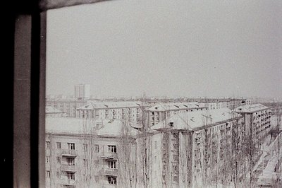Overlooking a winter cityscape with stark, Soviet-era apartment blocks covered in snow. Tall, linear architecture dominates t...