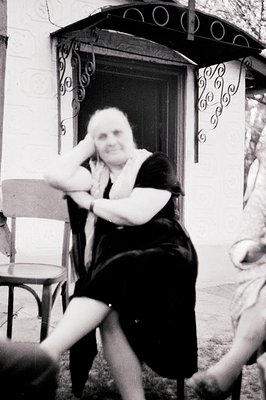 Woman seated on a wrought-iron chair in a decorative courtyard setting. The backdrop features an arched doorway with intricat...