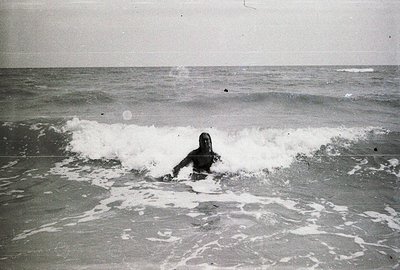 A surfer rides a wave, captured in a dynamic black and white image. The scene features frothy whitewater contrasting with the...