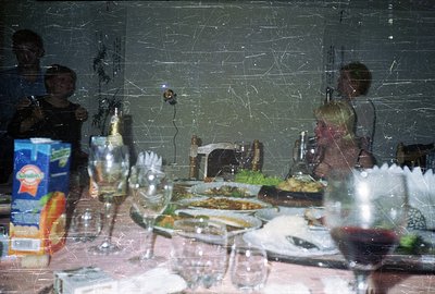 A candid snapshot depicts a family gathering; two children are visible, alongside beverage containers and a festive table set...