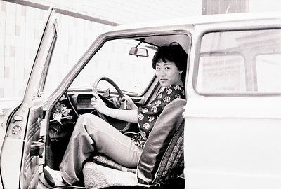 Here's a description of the photograph, following all the specified guidelines: A woman in wide-legged trousers & patterned s...