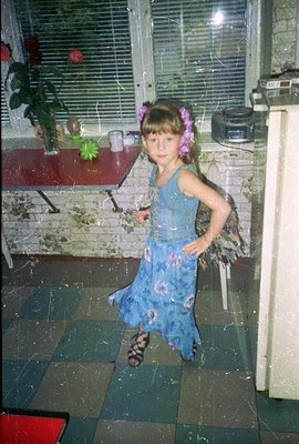 A young girl in a floral print dress, sandals, and floral headband stands confidently. Visible interior features include tile...