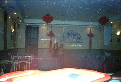 A banquet hall interior features elaborate Chinese decorations including red lanterns and a scroll depicting figures. Tables ...