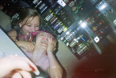A woman embraces a child, appearing distressed, in a brightly lit bar setting. Shelves stocked with liquor bottles are visibl...