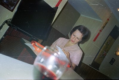 A young woman experiences motion blur while riding an amusement park ride, possibly a tilt-a-whirl. She wears a pink top & da...
