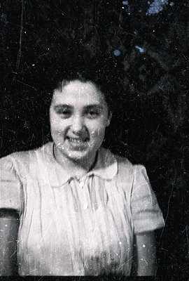 A portrait of a woman with a slight smile, dressed in a short-sleeved blouse. The image exhibits significant grain and visibl...
