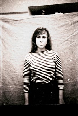 Striking black and white portrait of a young woman with dark hair and a striped long-sleeved shirt, set against a textured ba...