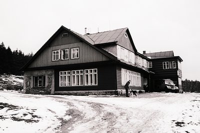 A large, chalet-style lodge sits amidst a snowy landscape. Dark wood siding, multi-paned windows, and a steeply pitched roof ...