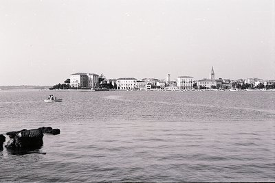 Panoramic view of a coastal town across calm water, likely the Black Sea. Buildings show a mix of architectural styles, inclu...