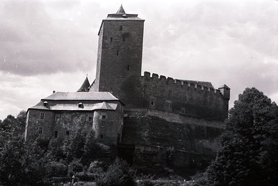 Dramatic, black & white view of Burgruine Heidenhain castle ruins, perched atop a steep, forested hill. Medieval defensive ar...