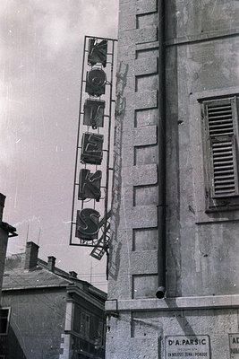 Vertical, illuminated "XYZ" sign affixed to a multi-story building exterior. Visible signage in Cyrillic script suggests a Ba...