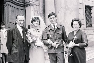 Formal portrait of a wedding party, likely 1960s. A formally dressed older man and woman flank a uniformed soldier and a brid...