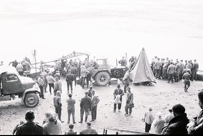 Crowd gathered outdoors near military vehicles and equipment, likely a training exercise or demonstration. Several men in uni...