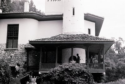A view of a two-story residence, showcasing a blend of Mediterranean and possibly Moorish architectural influences. Stone fou...