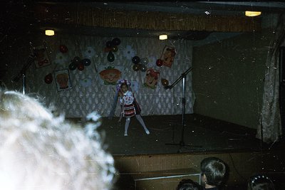 Vintage puppet theater stage featuring a marionette in a striped dress performing. Decor includes floral-patterned backdrop w...